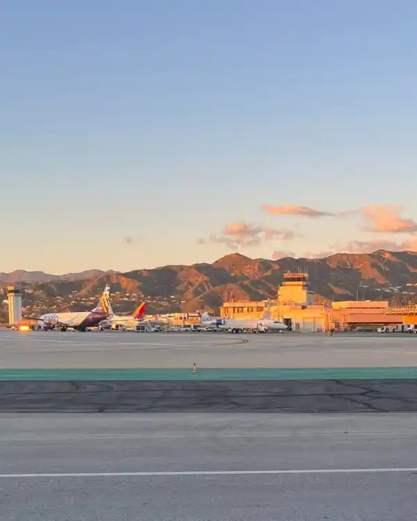 Hollywood Burbank Airport terminal and control tower at sunset, with mountains behind